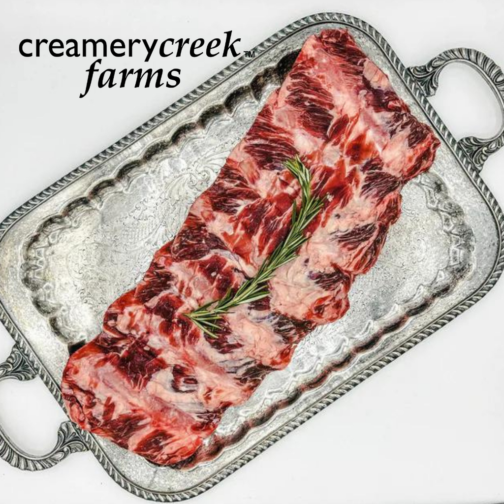 Beef back ribs on a silver platter, sprig of rosemary