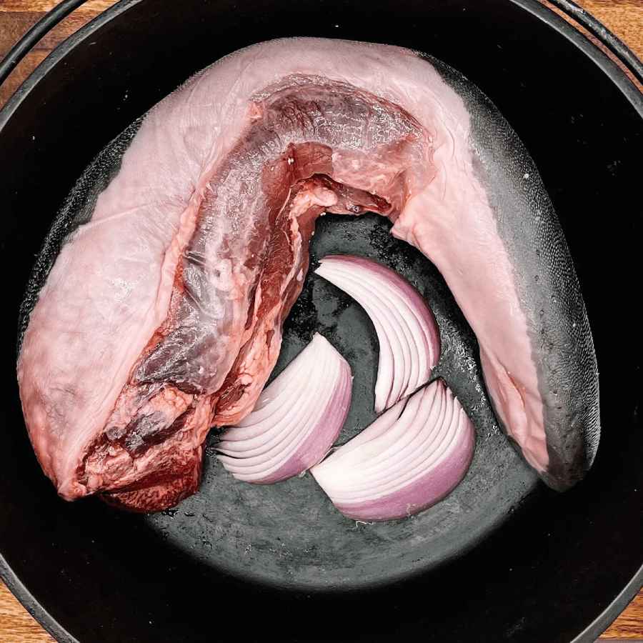 creamery creek beef tongue in a cast iron pot with some chopped purple onions