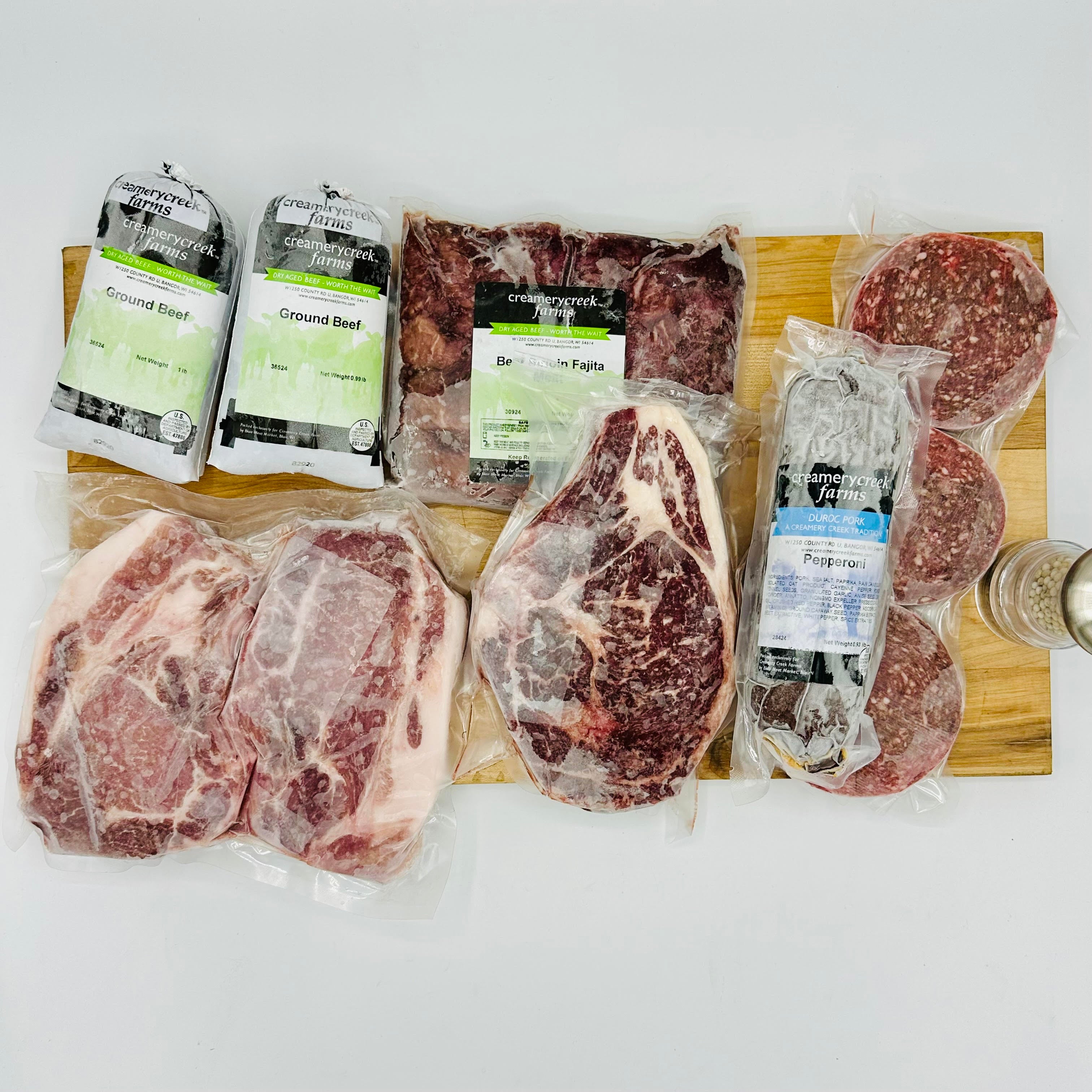 Assorted packaged meats on a wooden board with visible brand labels.
