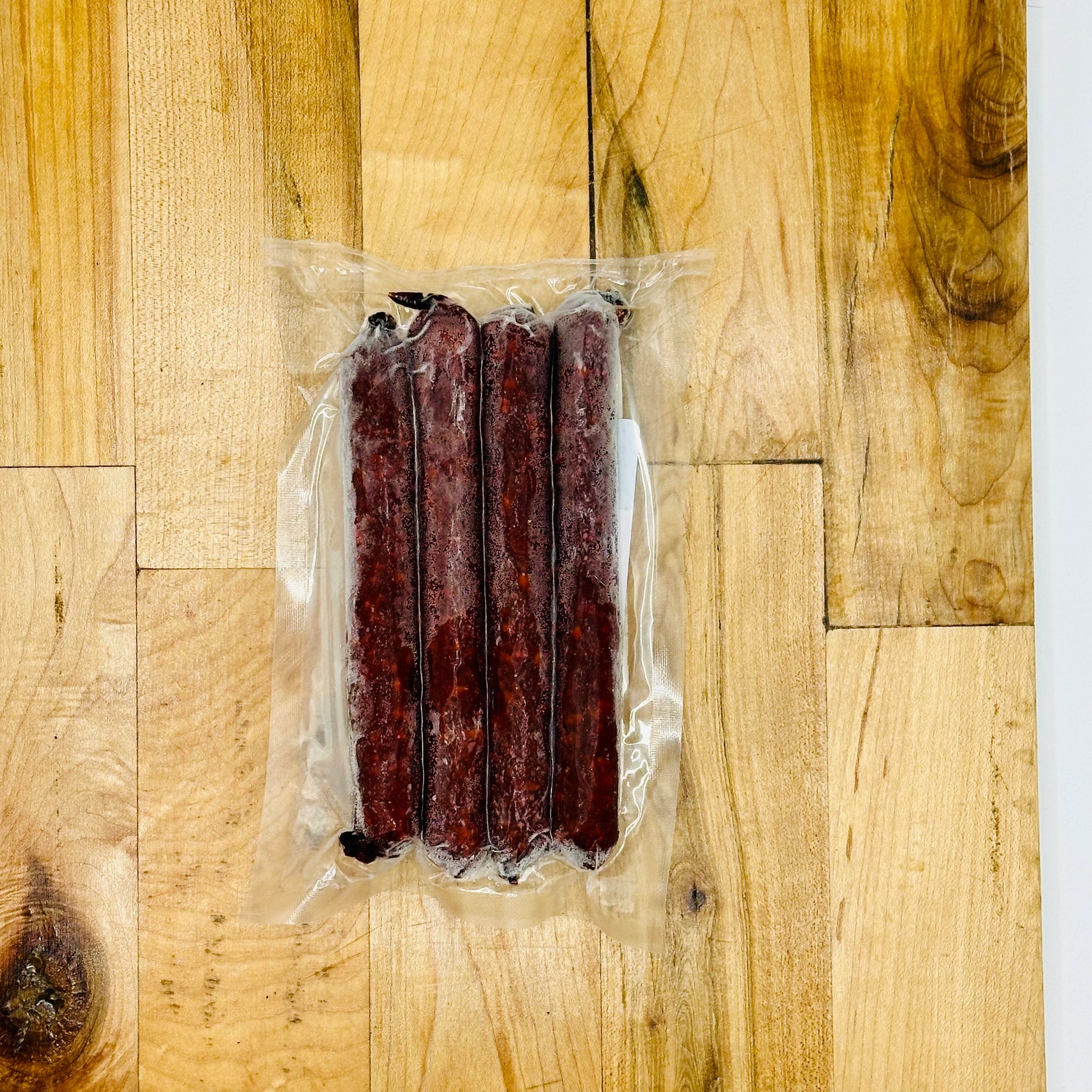 Vacuum-sealed package of sausages on a wooden surface