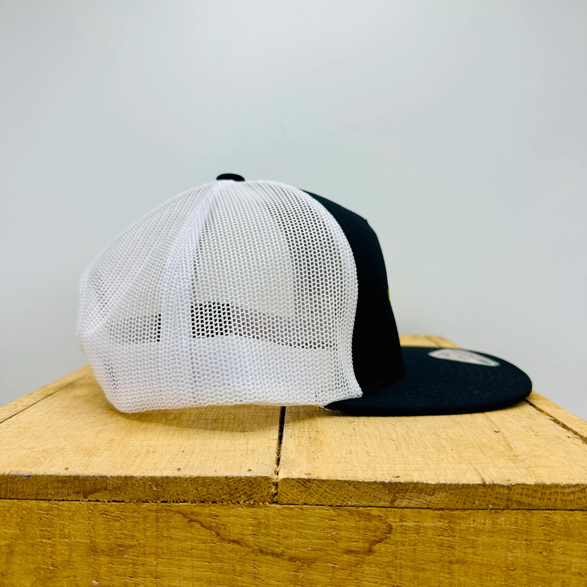 White and black cap on a wooden surface with a light gray background