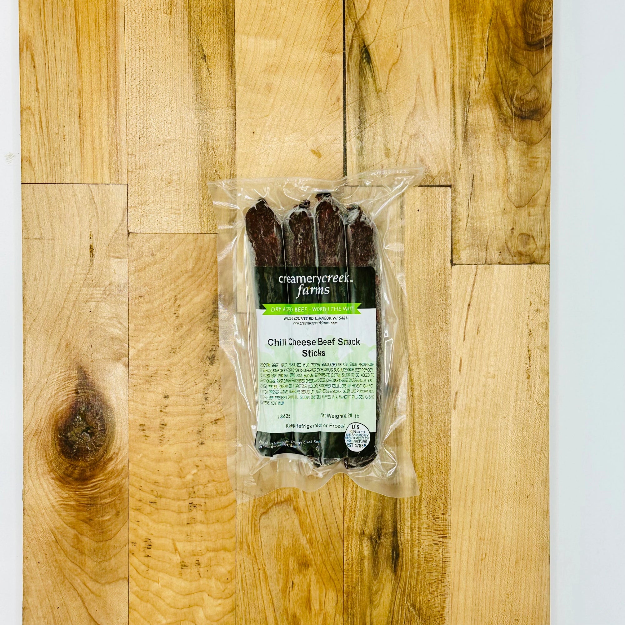 Packaged chili cheese beef stick sticks on a wooden surface