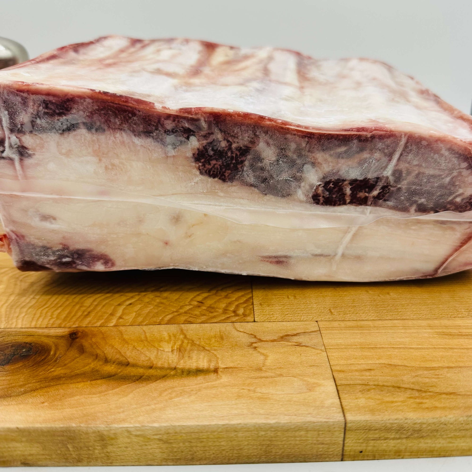 Raw meat on a wooden cutting board with a neutral background