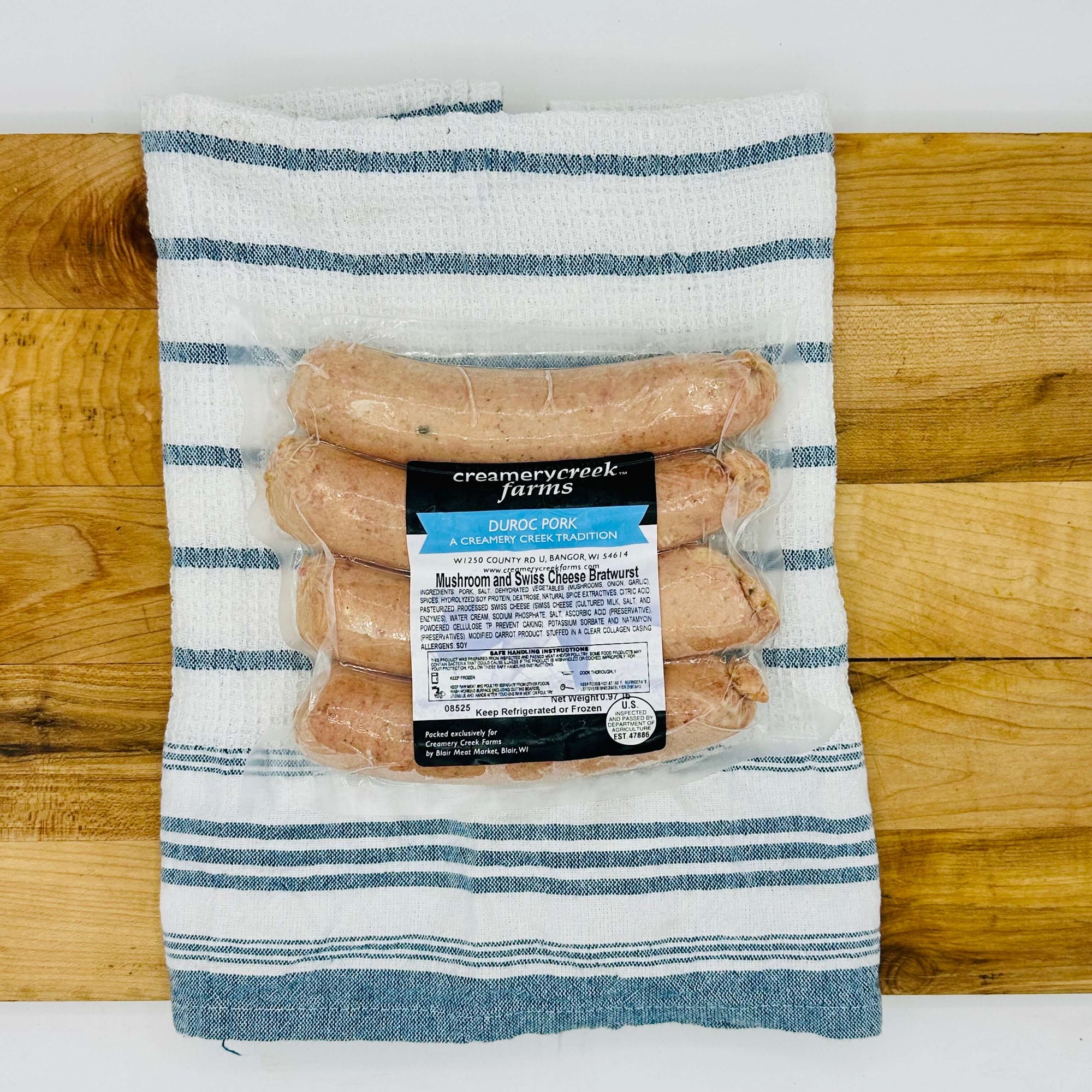Four fresh mushroom and Swiss Duroc pork bratwursts on a tray, uncooked—extra-large size with visible inclusions and clear collagen casing, ready for grilling.