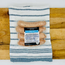 Four fresh mushroom and Swiss Duroc pork bratwursts on a tray, uncooked—extra-large size with visible inclusions and clear collagen casing, ready for grilling.