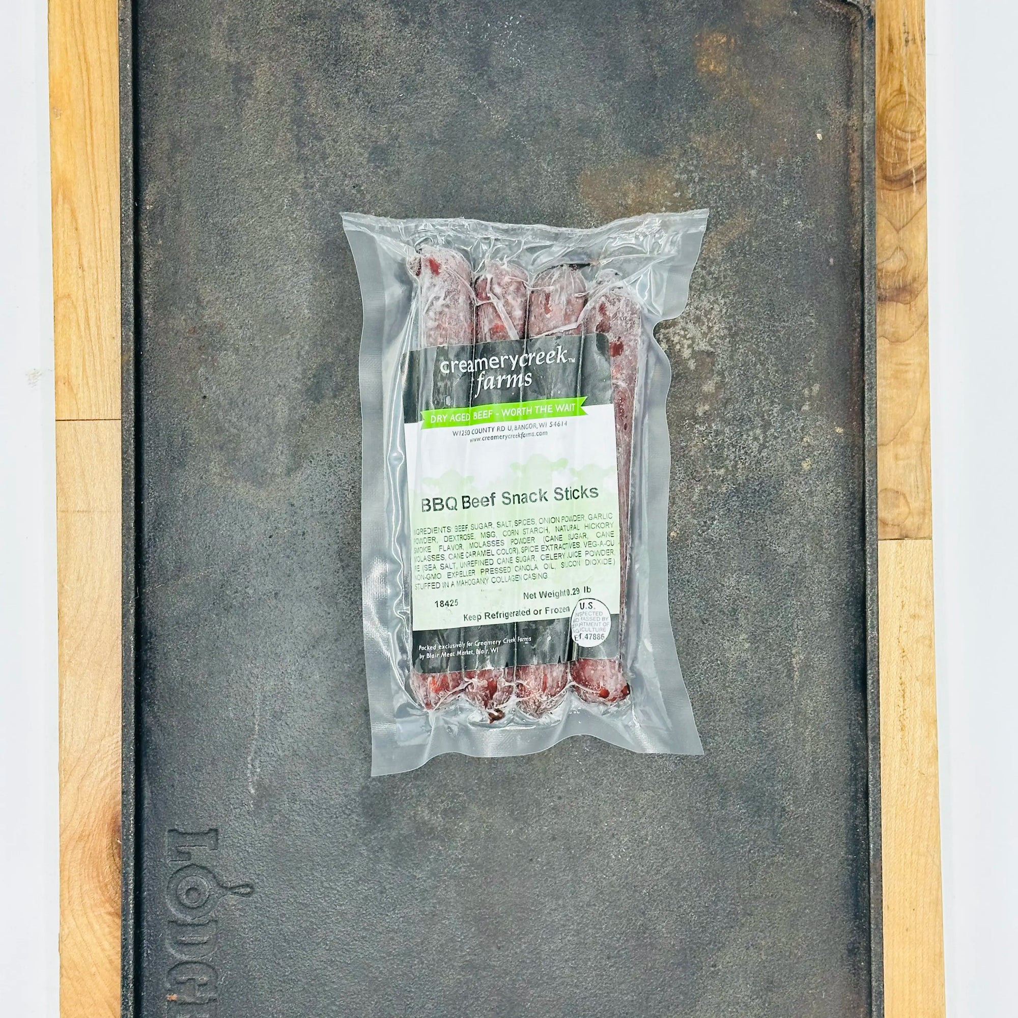Packaged BBQ Beef Snack Sticks from Creamy Creek Farms on a metal surface.