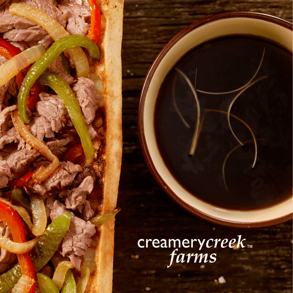 au jus dip paired with a beef sandwich with onions and peppers