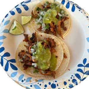 Two tacos with meat and guacamole on a decorative plate with blue patterns