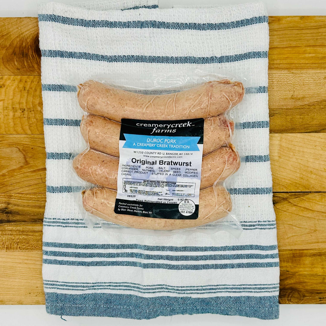 Four fresh Duroc pork bratwursts on a tray, uncooked and ready for the grill—extra-large size with natural marbling and clear collagen casing.