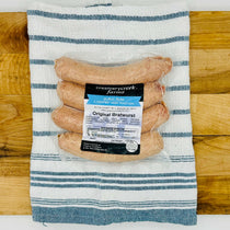 Four fresh Duroc pork bratwursts on a tray, uncooked and ready for the grill—extra-large size with natural marbling and clear collagen casing.