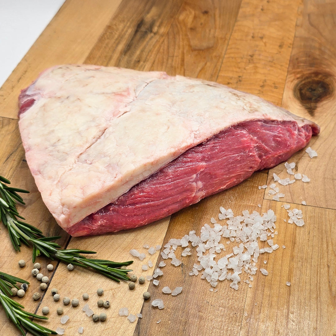 Raw beef on a wooden cutting board with rosemary and salt