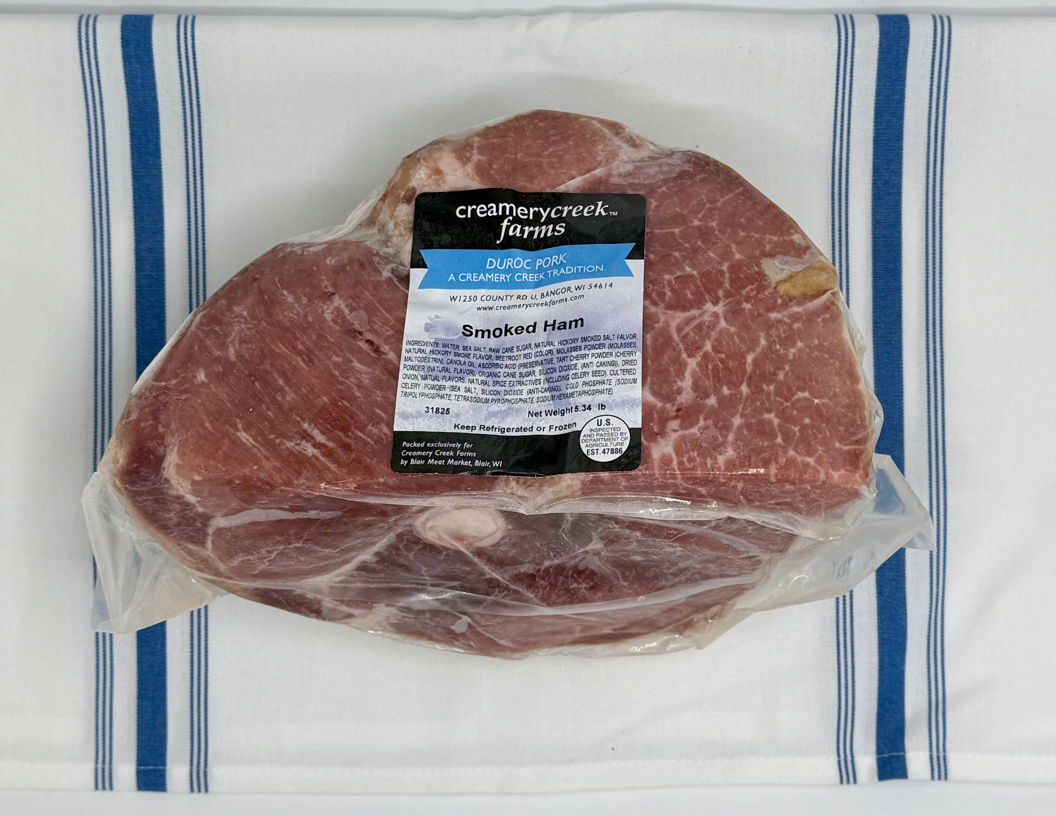 Packaged smoked ham with a label on a white and blue striped towel
