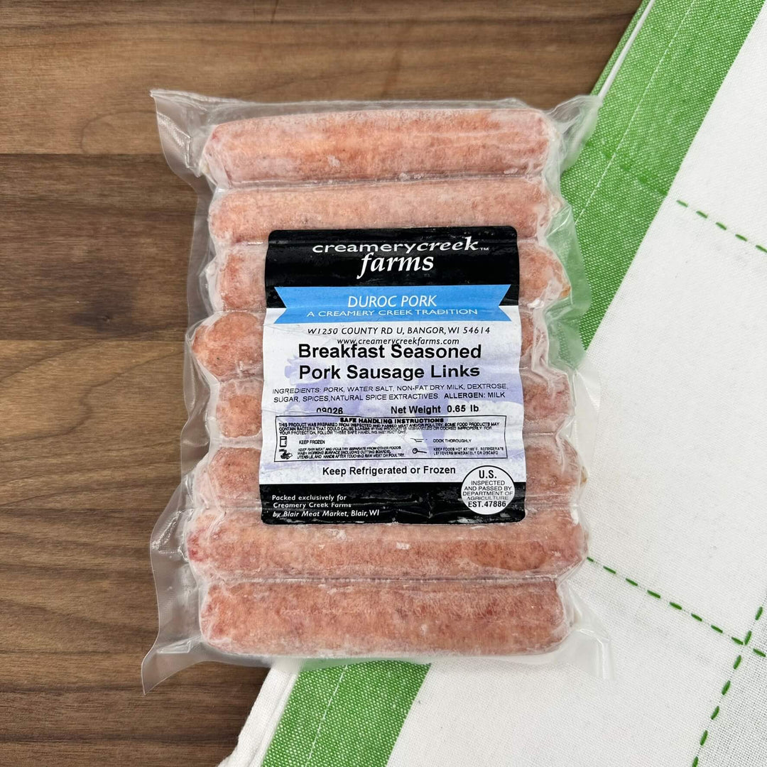 Packaged sausage links with Creamery Creek Farms label on a wooden surface