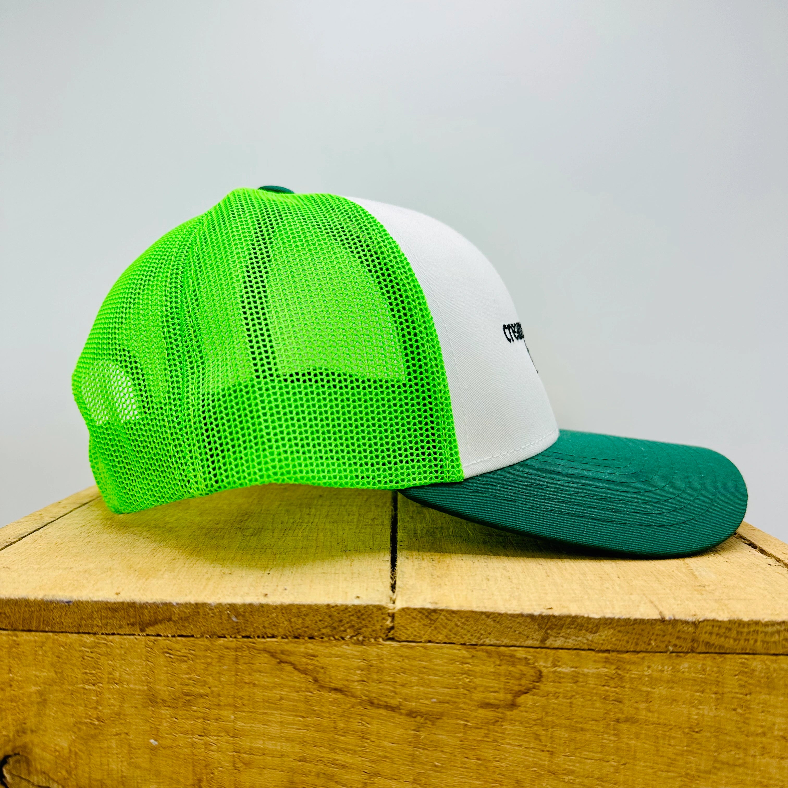 Green and white mesh cap on a wooden surface with a light gray background