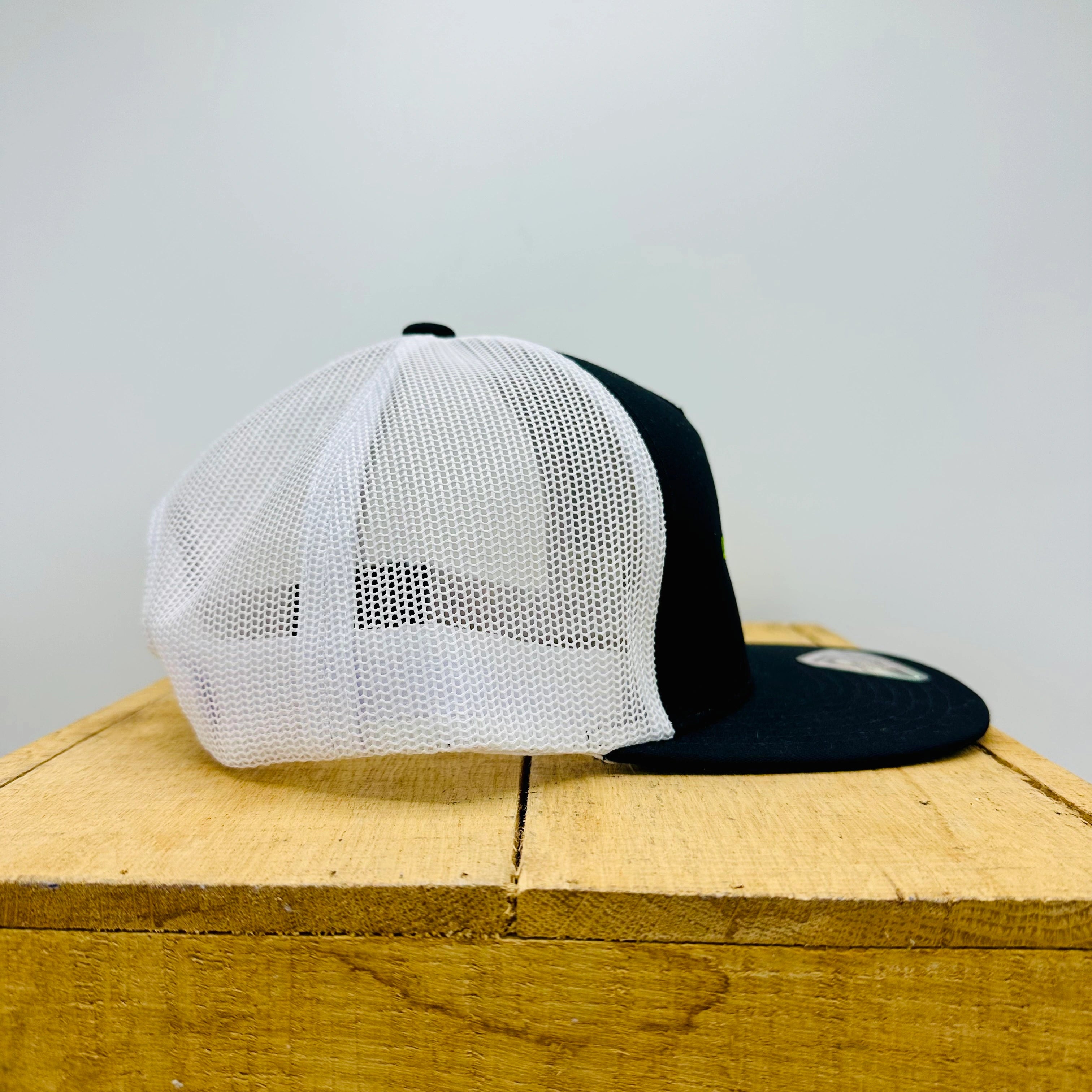 White and black cap on a wooden surface with a light gray background
