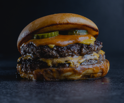 Double burger with cheese and pickles on a dark background