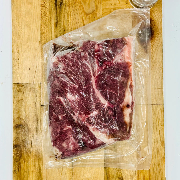 Vacuum-sealed raw steak on a wooden cutting board