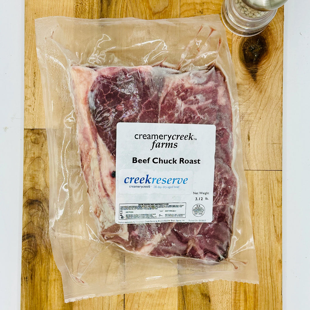 Packaged beef chuck roast from Creamery Creek Farms on a wooden cutting board.