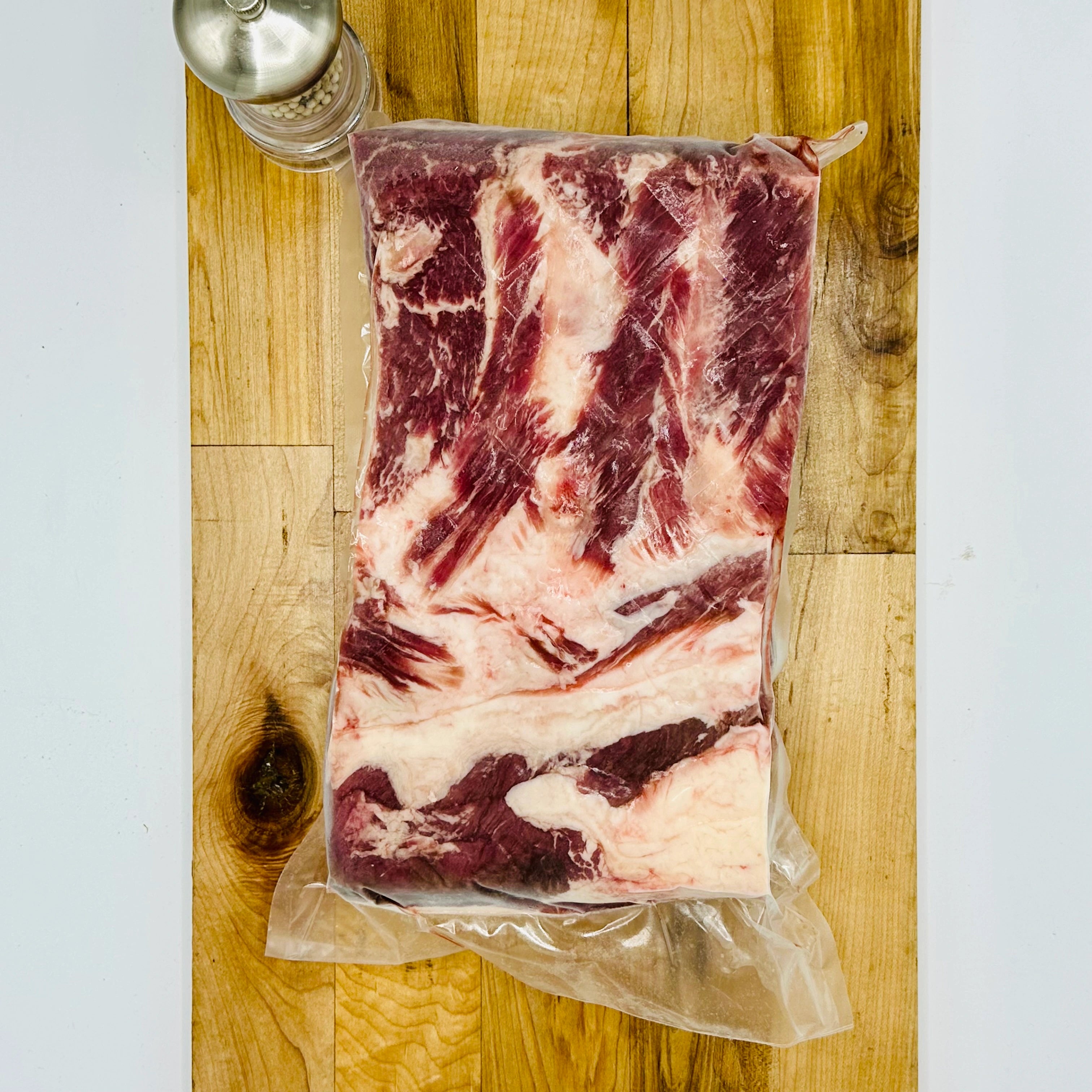Vacuum-sealed package of raw beef on a wooden cutting board