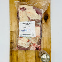 Packaged beef brisket from Creamery Creek Farms on a wooden cutting board.