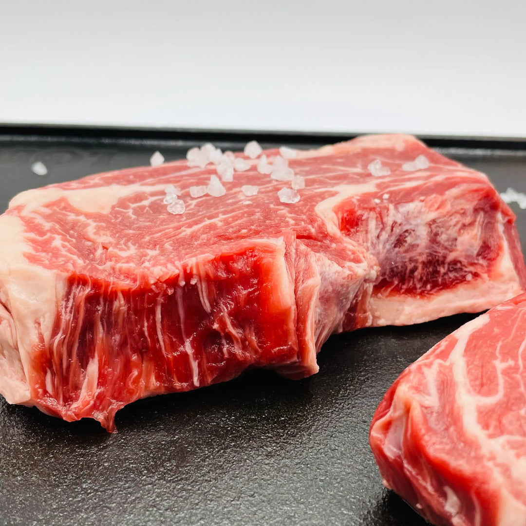 Raw chuckeye steak with salt crystals on a dark surface