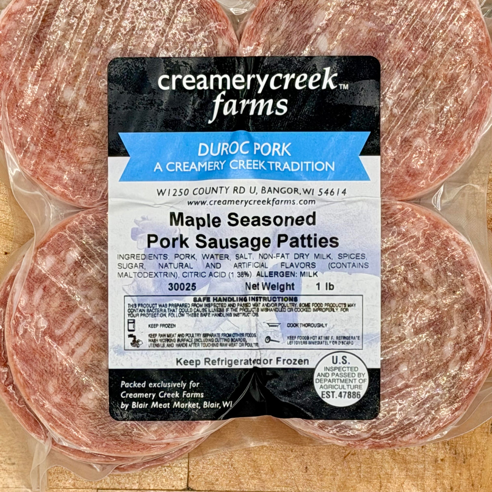 Packaged Maple Seasoned Pork Sausage Patties with Creamery Creek Farms label on a wooden surface.