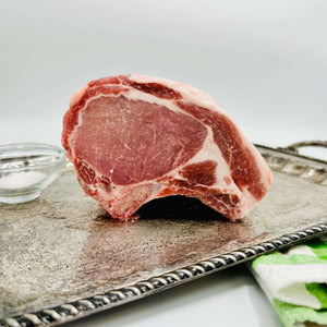 Raw pork chop roast on a metallic tray with a white background