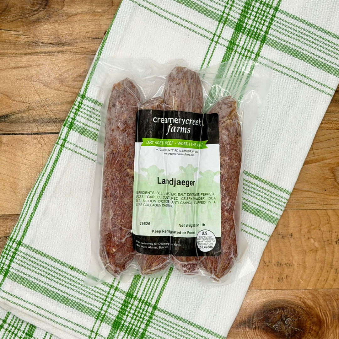 Packaged Landjaeger from Creamerycreek Farms on a wooden surface with a green and white checkered towel.