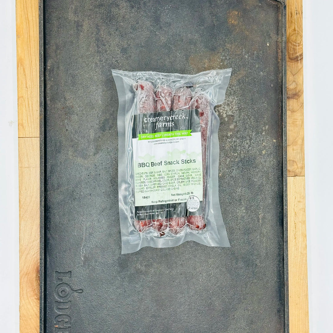 Packaged BBQ Beef Snack Sticks from Creamy Creek Farms on a metal surface.