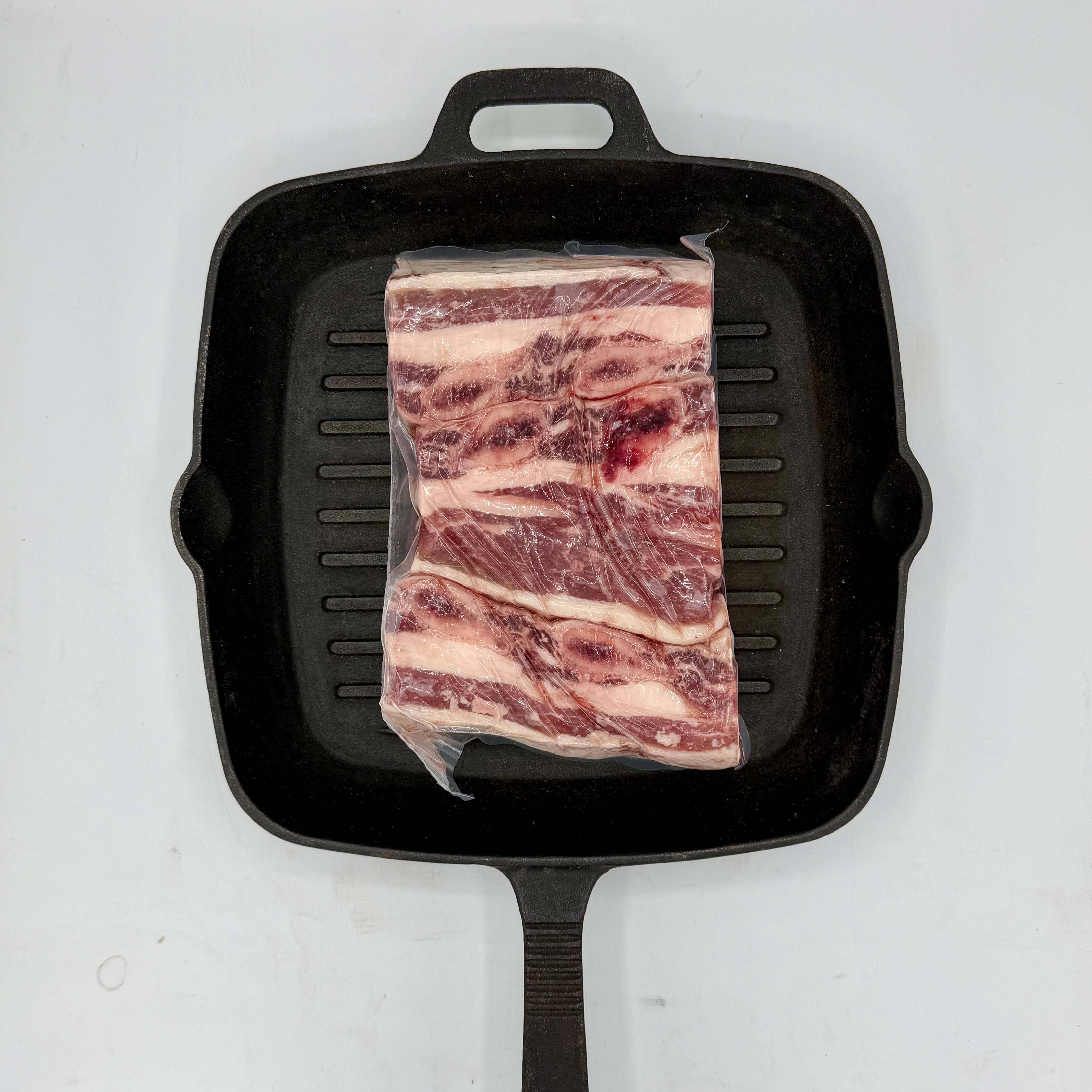 Raw meat on a black grill pan on a white background