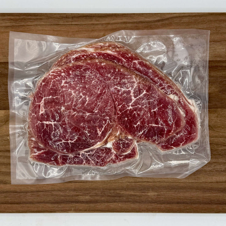 Vacuum-sealed package of corned beef on a wooden surface