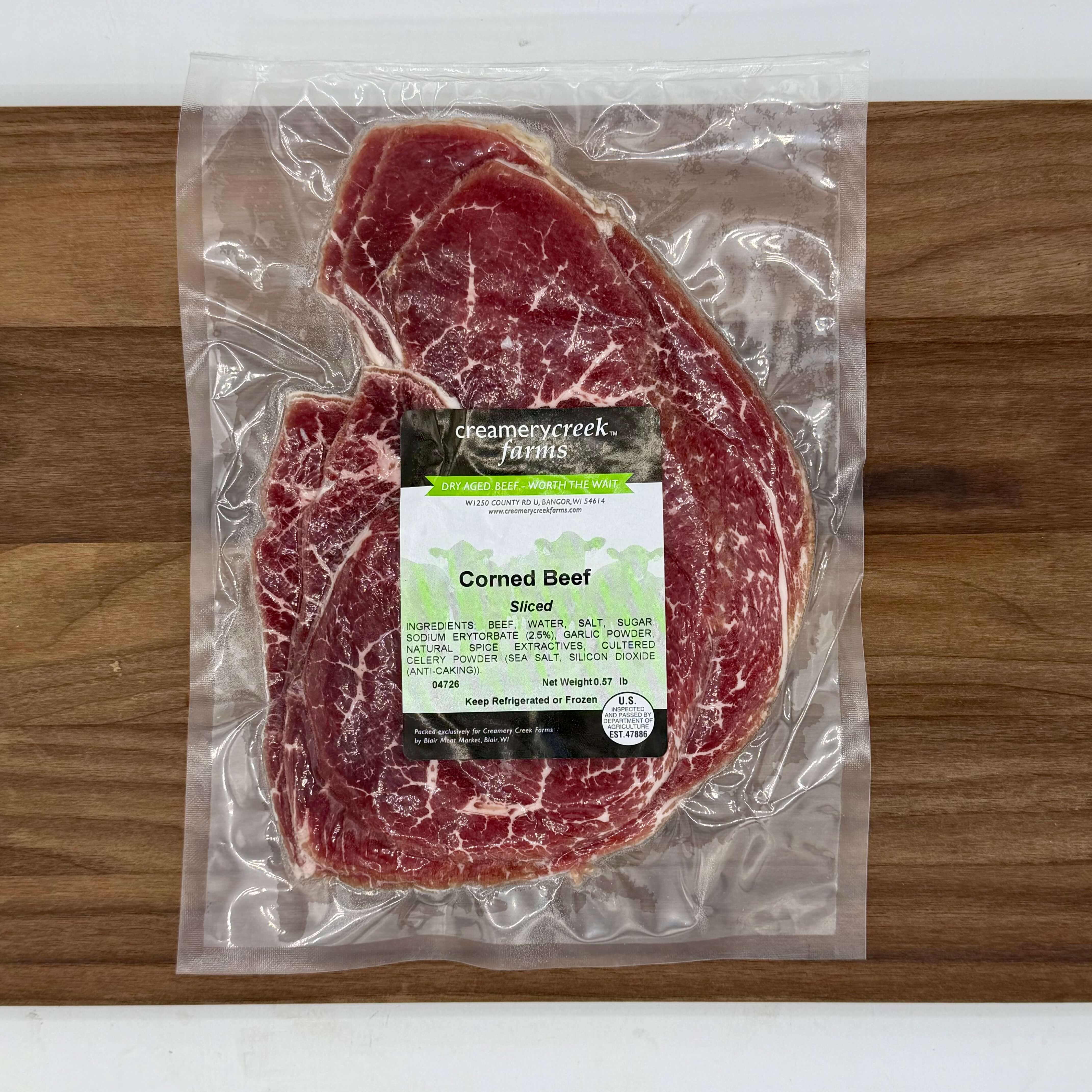 Vacuum-sealed corned beef on a wooden surface with a label.