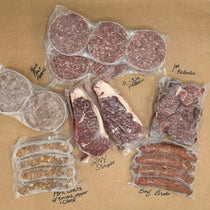 Assorted packaged Creamery Creek beef and pork meats on a kraft paper 